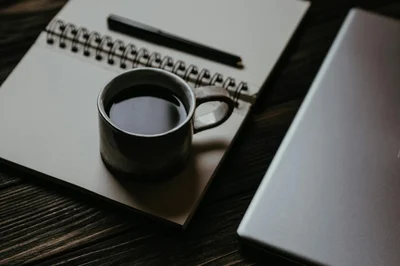 A cozy workspace with a coffee cup, notebook, and laptop, ideal for productivity.